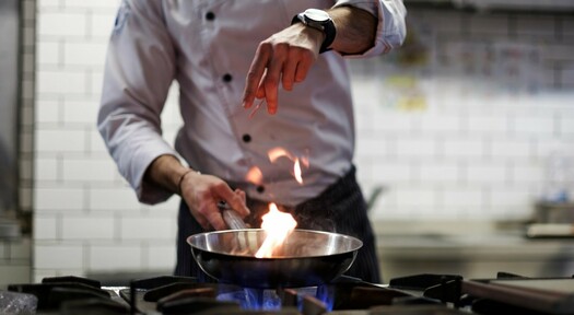 Koch beim braten an einem Gasherd.