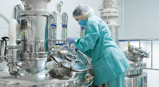 Frau arbeitet unter sterilen Bedingungen in der Produktion eines Pharmaunternehmens, welches Flüssiggas als Prozessenergie nutzt.