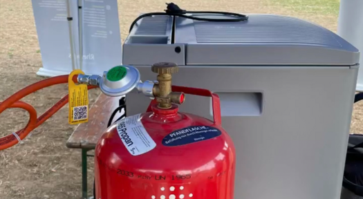Eine rote Rheingas Gasflasche kühlt einen Gaskühlschrank.