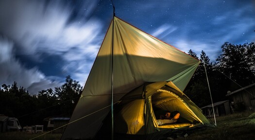 Camping-Zelt bei Nacht hinter dem Campinggas von Rheingas steht.