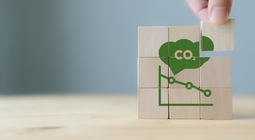 Ein Puzzle aus Holzstücken, welches einen fallenden CO2-Graphen zeigt.