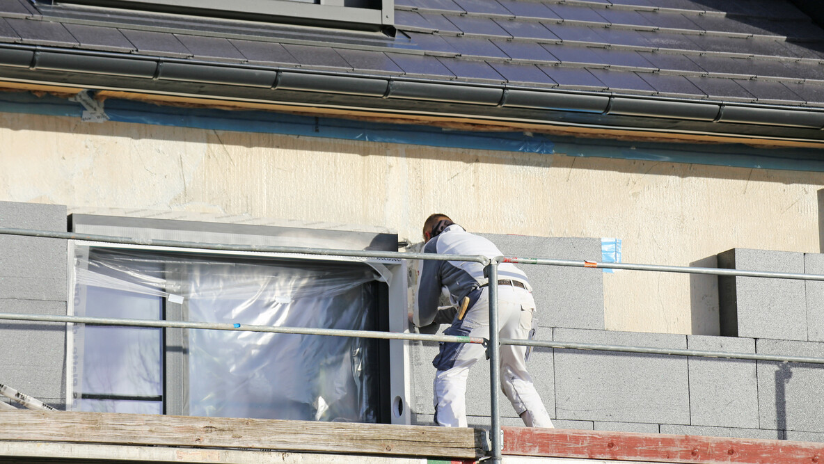 Handwerker bei der Fassadendämmung eines Mehrfamilienhauses.