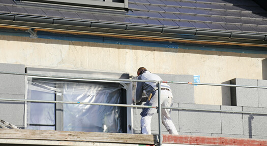 Handwerker bei der Fassadendämmung eines Mehrfamilienhauses.