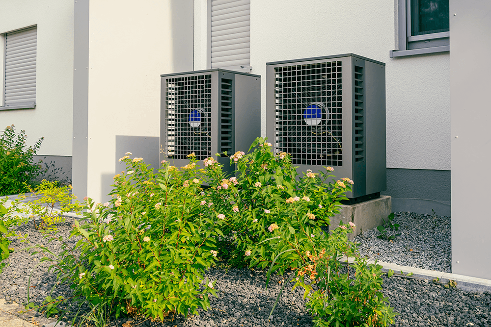 Moderne Luftwärmepumpen hinter einem Haus.